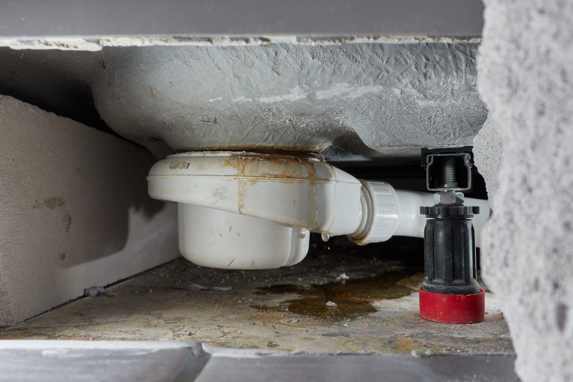 Waste fitting under a shower tray with a water droplet